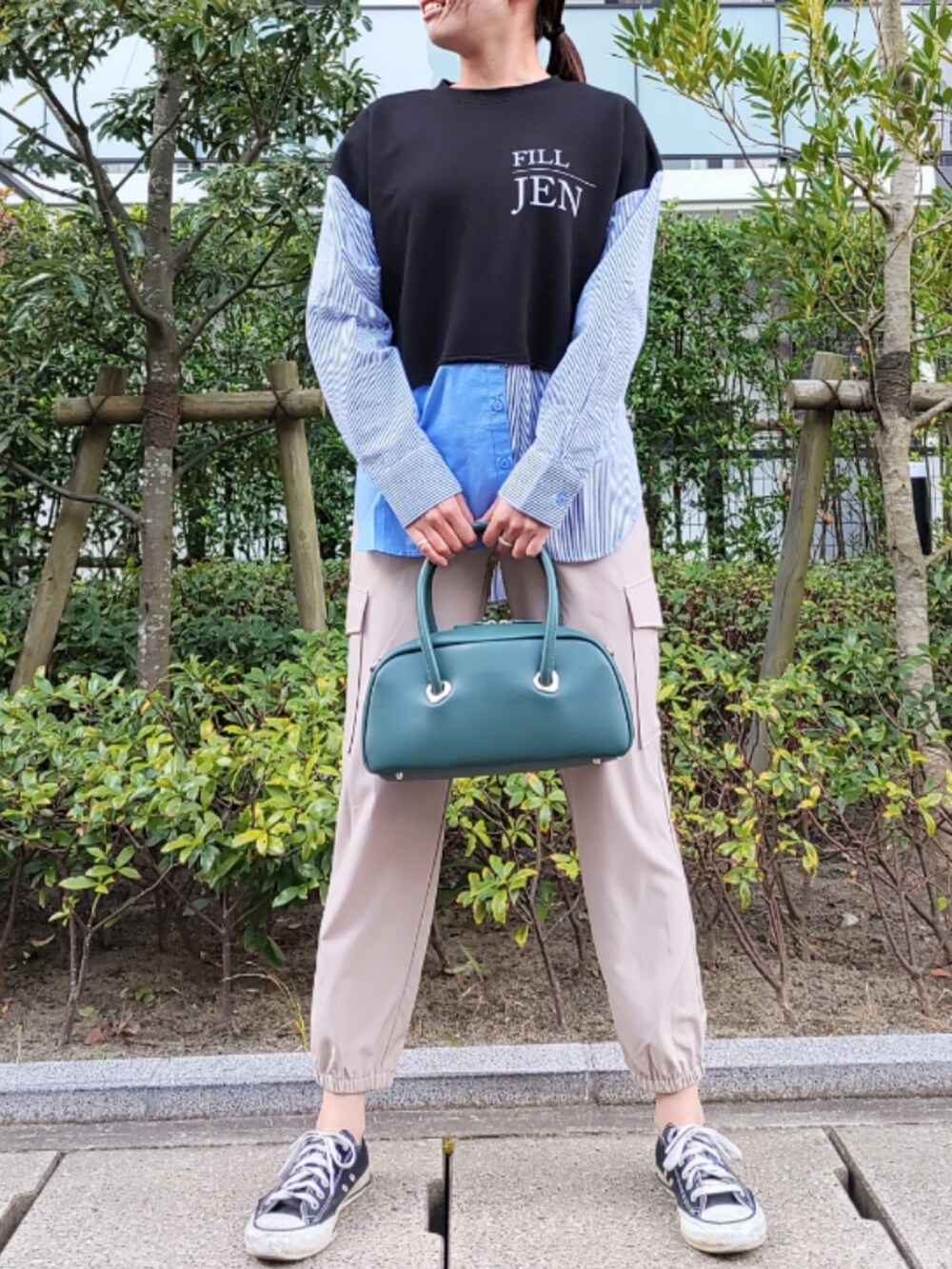 ベージュ系のカーゴパンツ、ブラック系のスニーカー、グリーン系のボストンバッグを着用したレディースの秋コーディネートの2枚目の写真