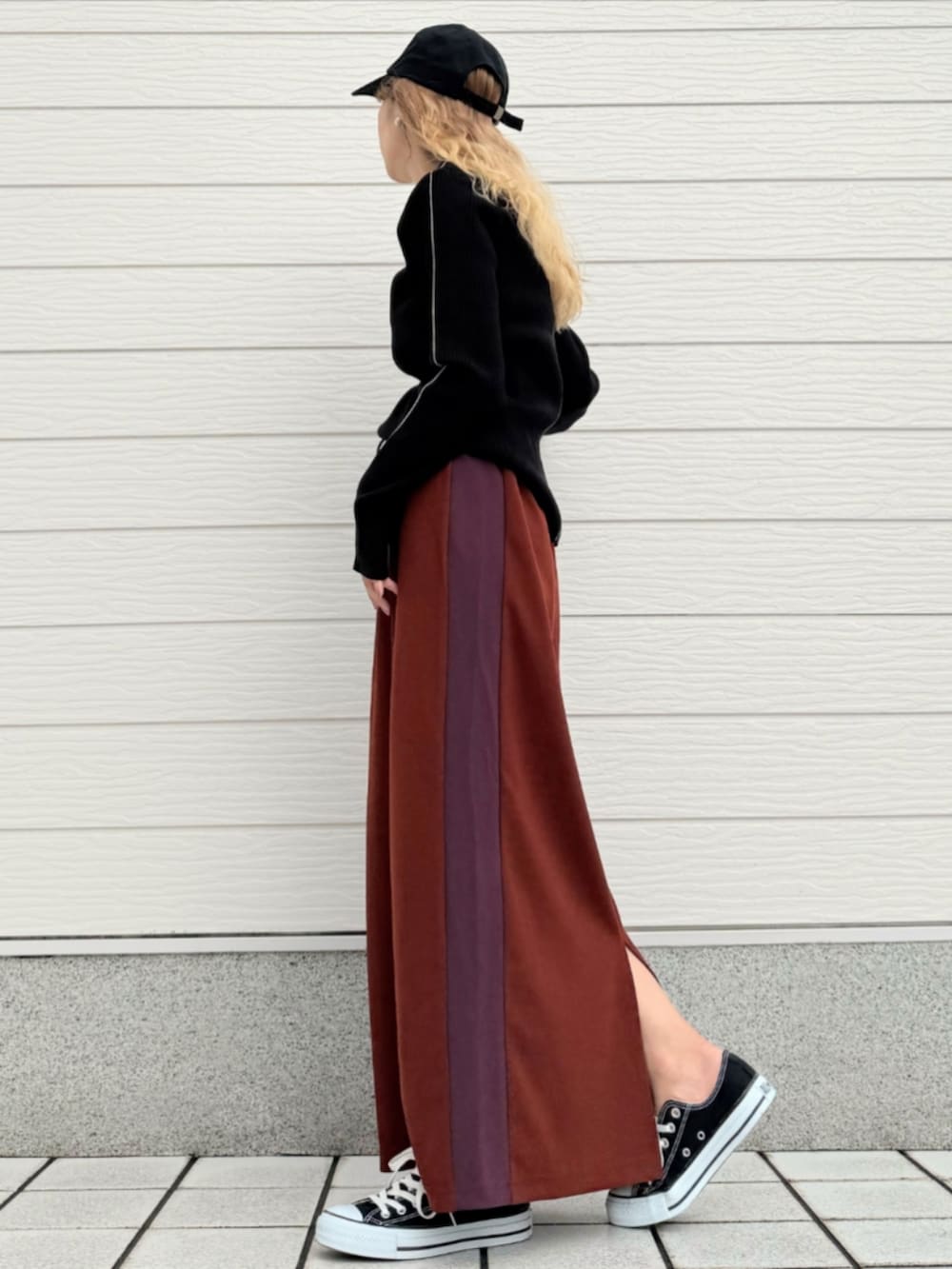 ブラック系のスニーカー、ブラック系のニット/セーター、ブラウン系のスカートを着用したレディースの秋コーディネートの2枚目の写真