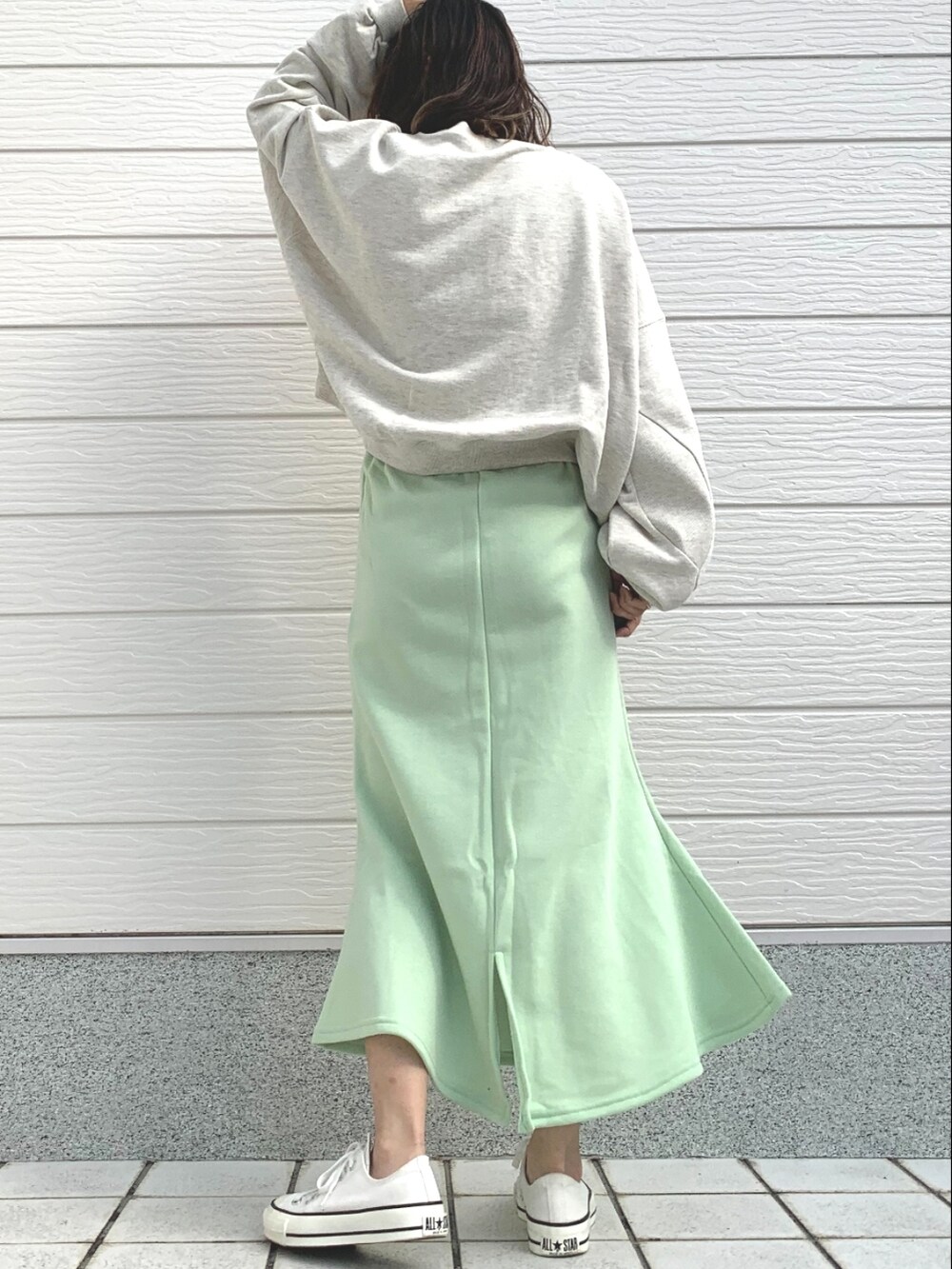 グリーン系のスカート、グレー系のスウェット、ホワイト系のスニーカーを着用したレディースの冬コーディネートの3枚目の写真