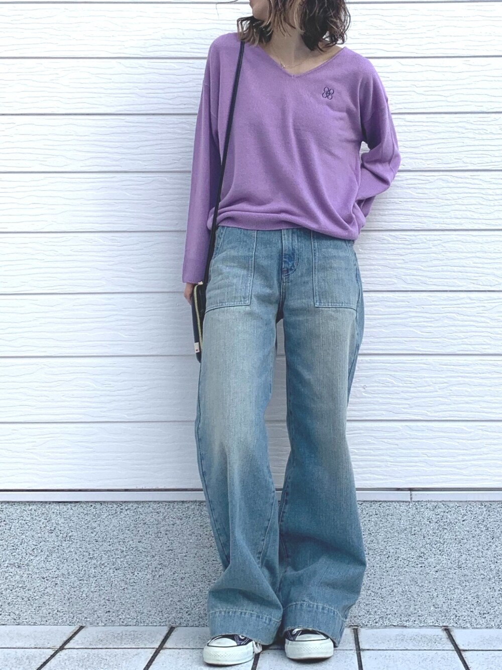 ブラック系のスニーカー、ブラック系のショルダーバッグ、ブルー系のデニムパンツを着用したレディースの冬コーディネートの4枚目の写真