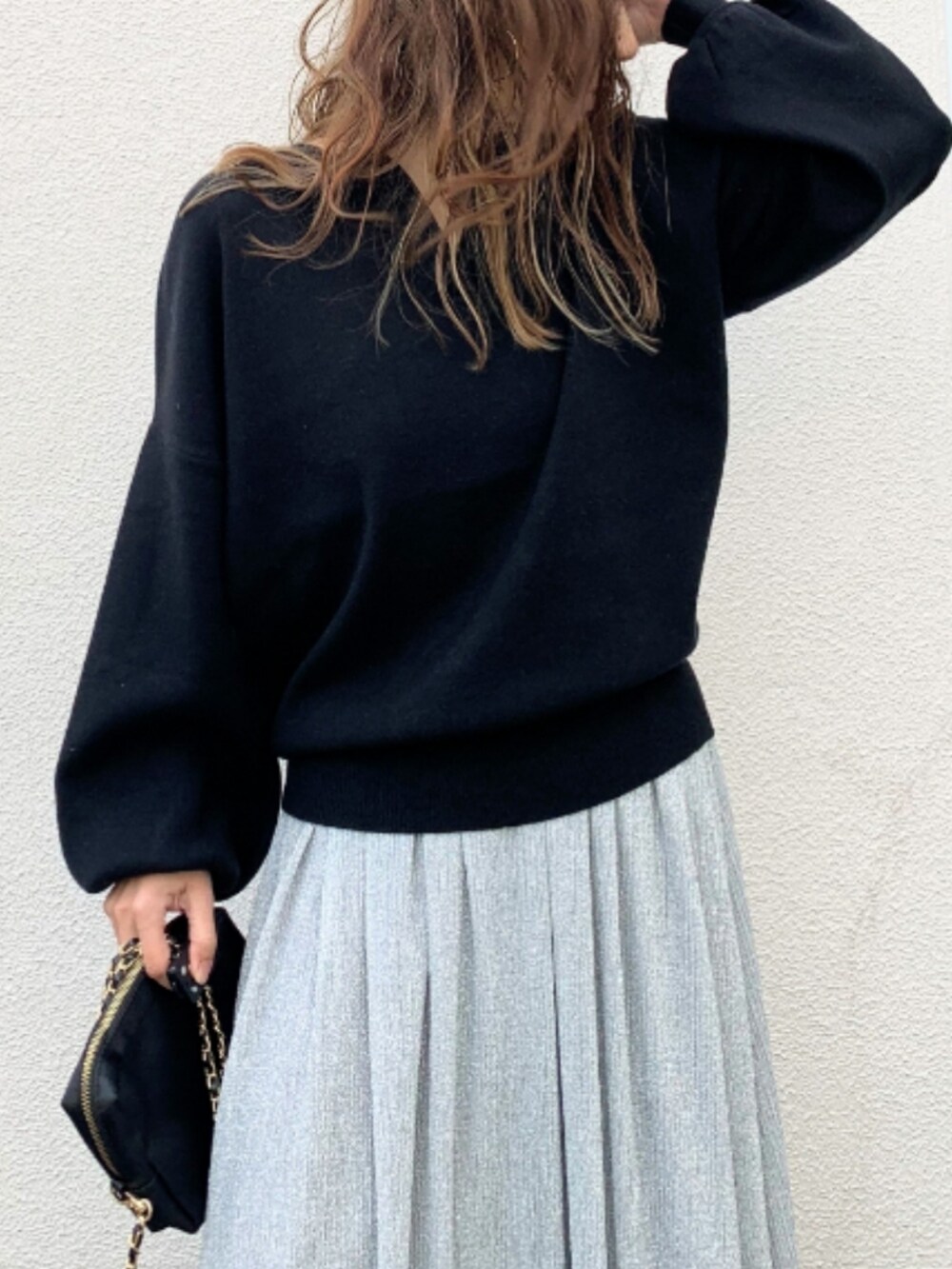 シルバー系のスカート、シルバー系のスニーカー、ブラック系のニット/セーターを着用したレディースの冬コーディネートの3枚目の写真