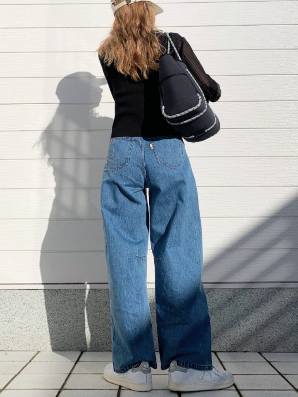 ブルー系のデニムパンツ、ホワイト系のスニーカー、ブルー系のトートバッグを着用したレディースの冬コーディネートの2枚目の写真