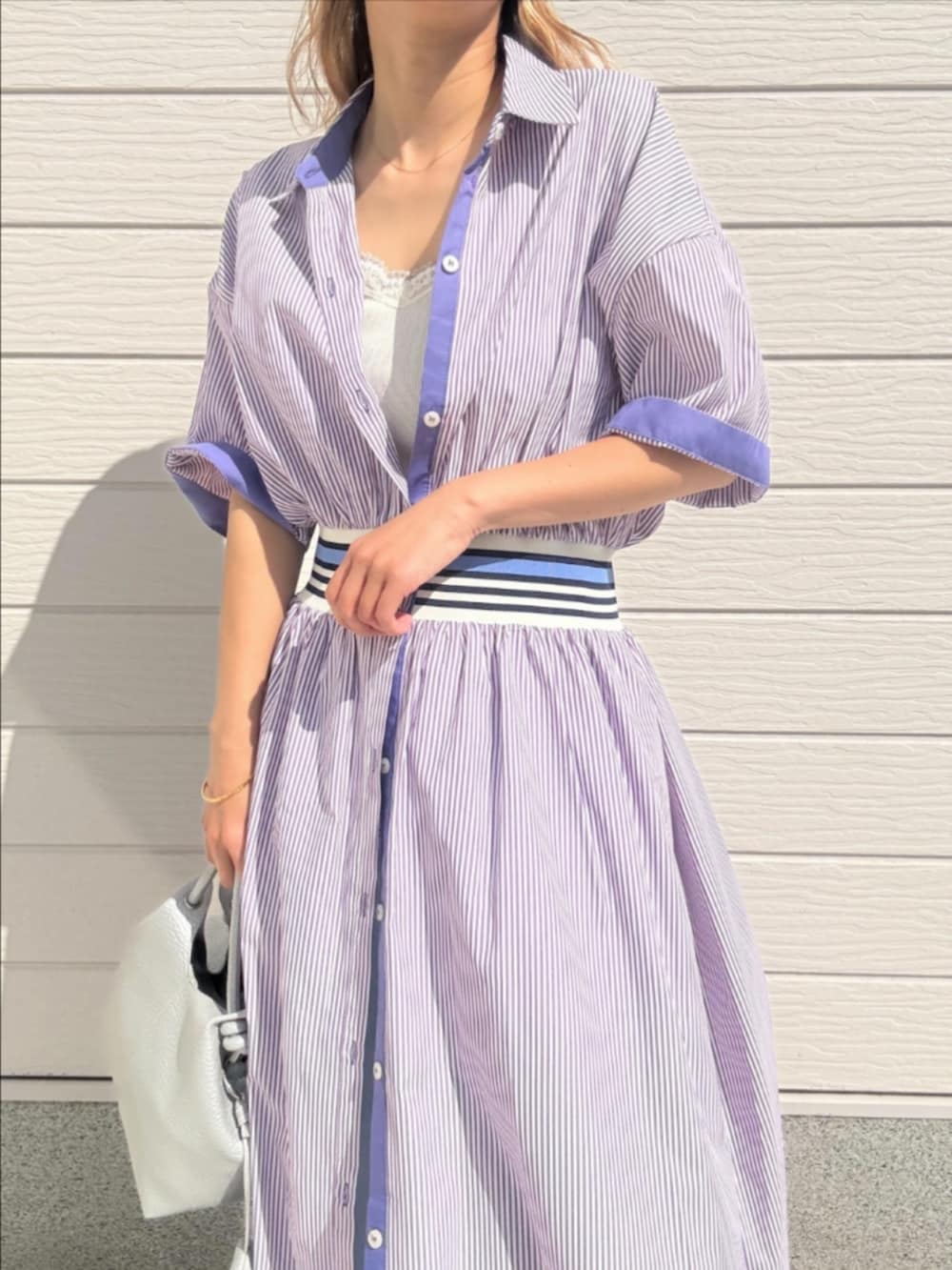 ブルー系のデニムパンツ、シルバー系のトートバッグ、パープル系のワンピースを着用したレディースの春コーディネートの5枚目の写真