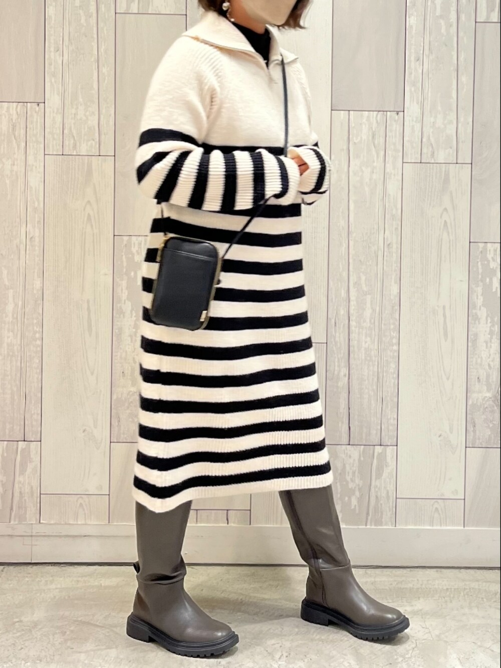 ブラック系のショルダーバッグ、ブラック系のワンピース、グレー系のブーツを着用したレディースの冬コーディネートの3枚目の写真