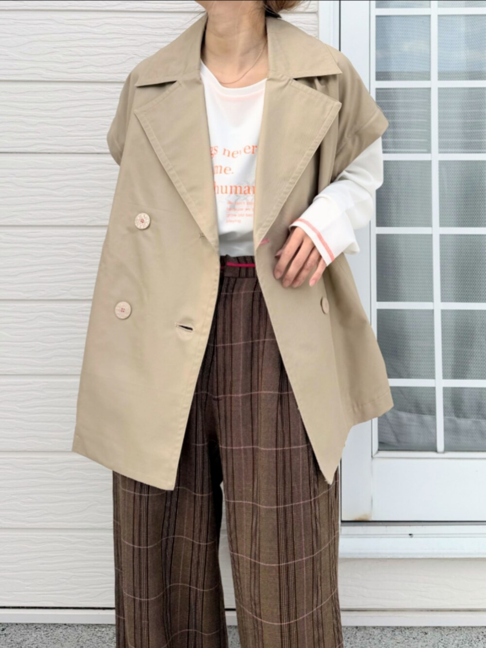 ホワイト系のTシャツ/カットソー、ベージュ系のトレンチコート、ブラウン系のスラックスを着用したレディースの冬コーディネートの4枚目の写真