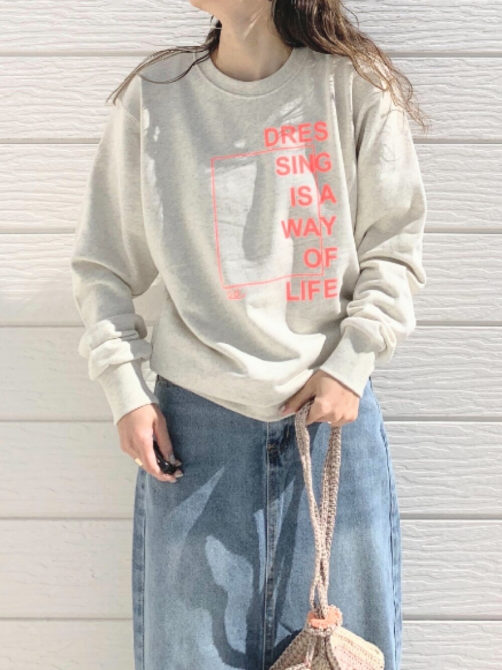 ベージュ系のスウェット、ブルー系のデニムスカート、ホワイト系のスニーカーを着用したレディースの春コーディネートの3枚目の写真