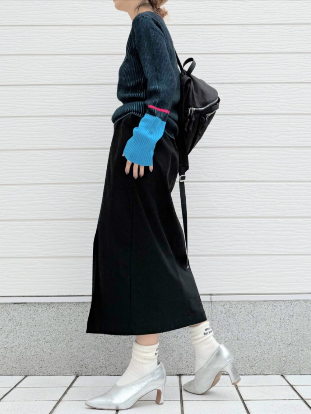 ブラック系のスカート、ブラック系のバックパック/リュック、ブラック系のニット/セーターを着用したレディースの秋コーディネートの2枚目の写真