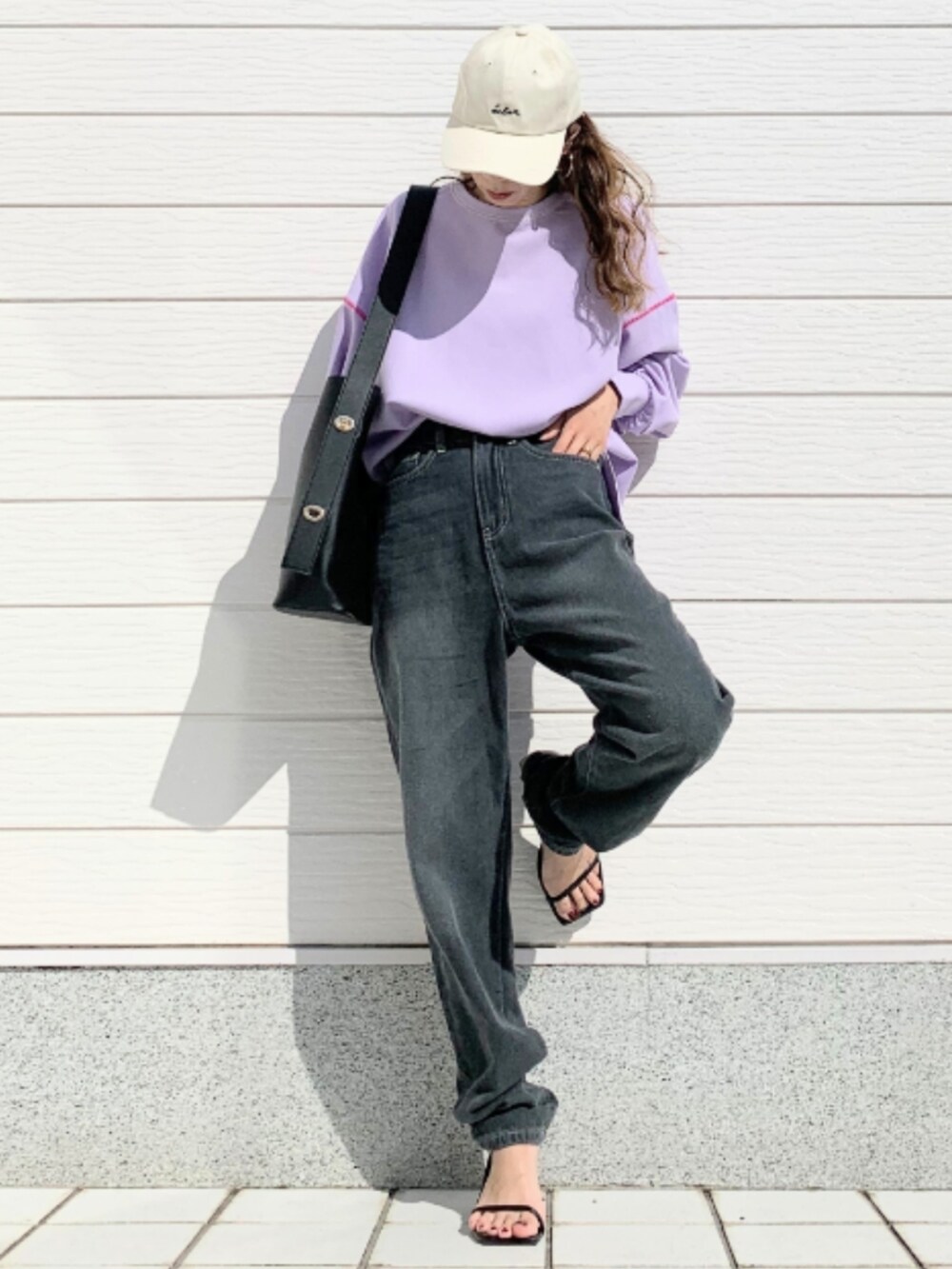 グレー系のデニムパンツ、ブラック系のトートバッグ、パープル系のTシャツ/カットソーを着用したレディースの春コーディネートの2枚目の写真