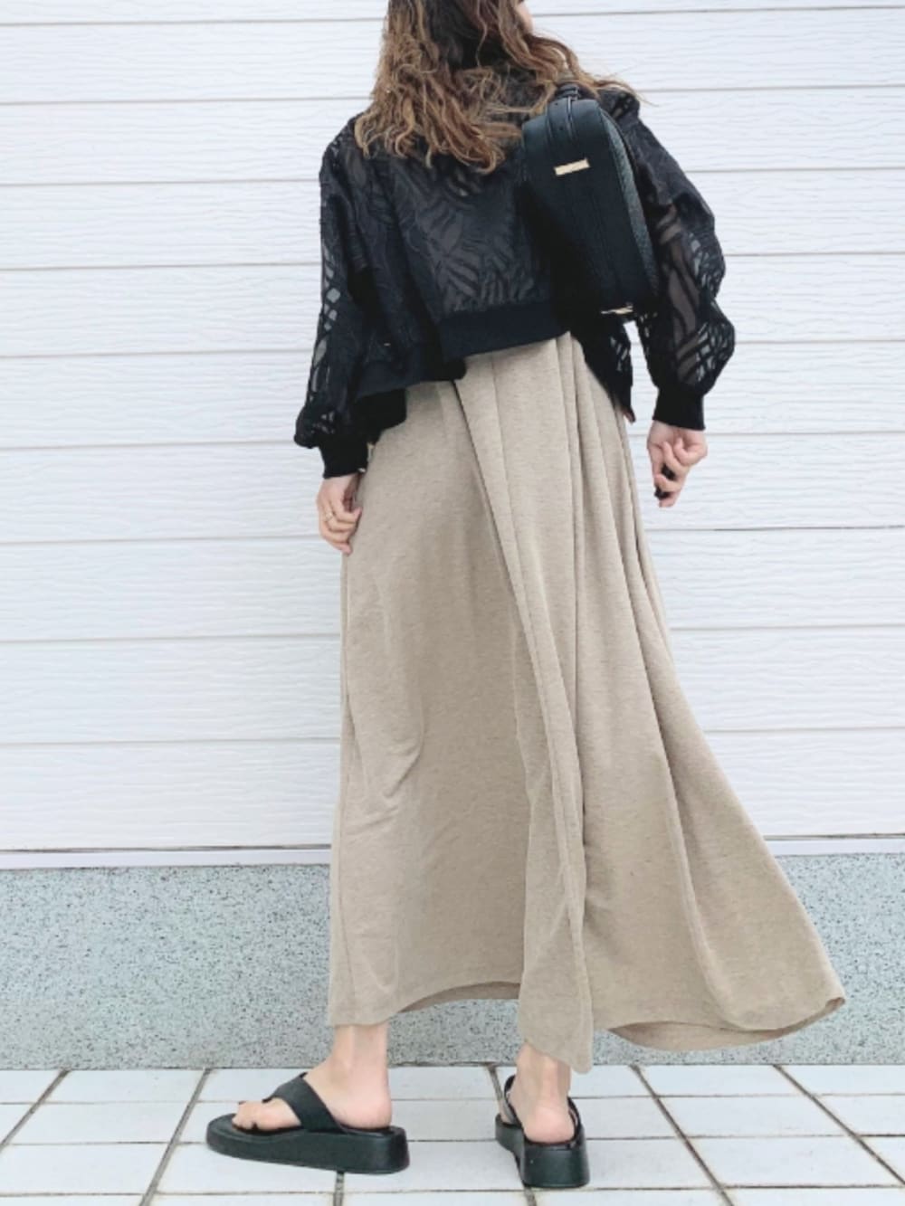 ブラック系のショルダーバッグ、ベージュ系のワンピース、ブラック系のブルゾンを着用したレディースの春コーディネートの3枚目の写真