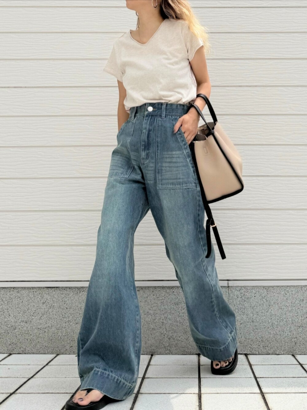 ブルー系のデニムパンツ、ベージュ系のハンドバッグ、ホワイト系のTシャツ/カットソーを着用したレディースの夏コーディネートの2枚目の写真