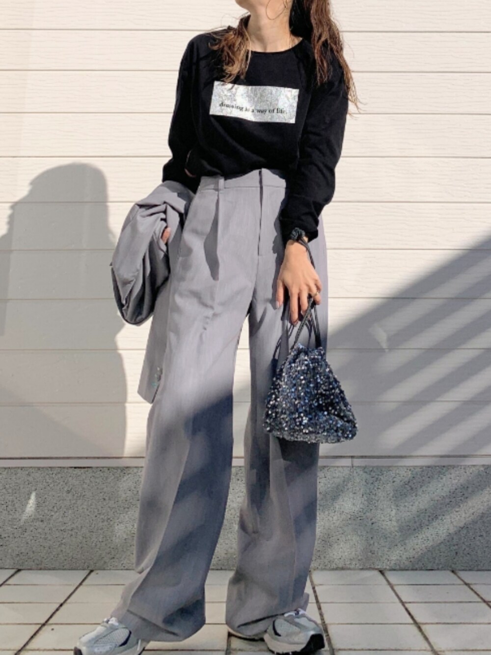 シルバー系のスニーカー、グレー系のスラックス、グレー系のテーラードジャケットを着用したレディースの冬コーディネートの2枚目の写真