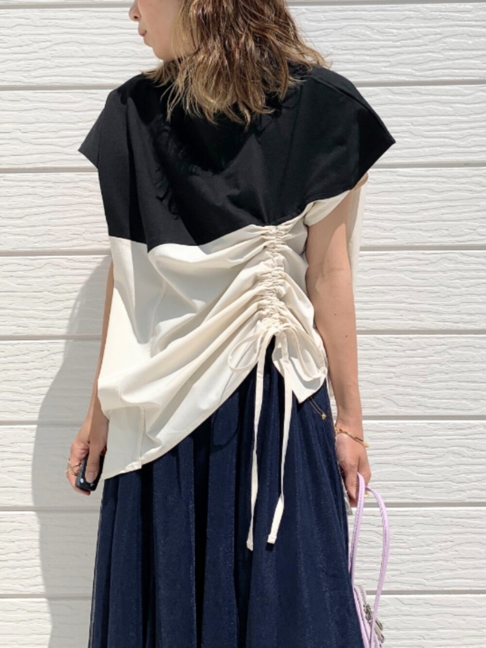 パープル系のショルダーバッグ、ブラック系のサンダル、ブルー系のスカートを着用したレディースの春コーディネートの3枚目の写真