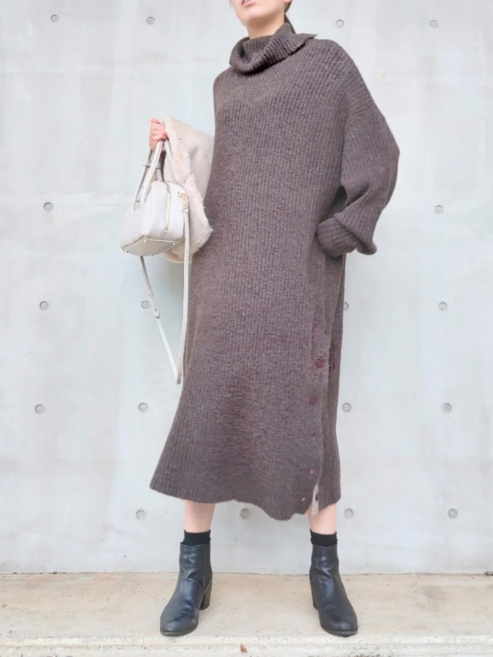 ホワイト系のボストンバッグ、ベージュ系のベスト、ブラウン系のワンピースを着用したレディースの秋コーディネートの3枚目の写真