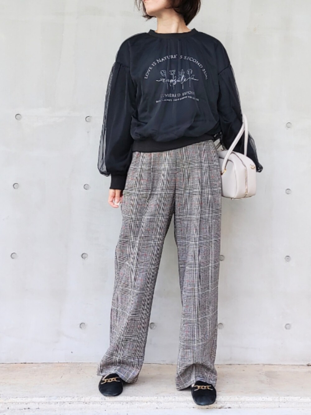 ブラック系のスラックス、ブラック系のスウェット、ホワイト系のボストンバッグを着用したレディースの秋コーディネートの2枚目の写真