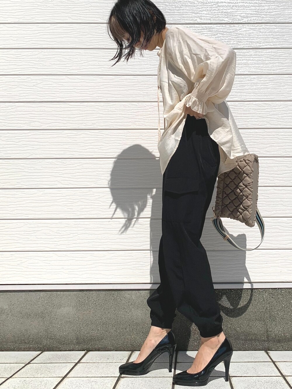 ベージュ系のショルダーバッグ、ホワイト系のシャツ/ブラウス、ブラック系のカーゴパンツを着用したレディースの夏コーディネートの2枚目の写真