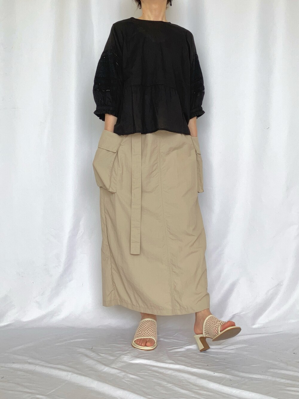 ブラック系のシャツ/ブラウス、ベージュ系のスカート、グレー系のサンダルを着用したレディースの夏コーディネートの2枚目の写真