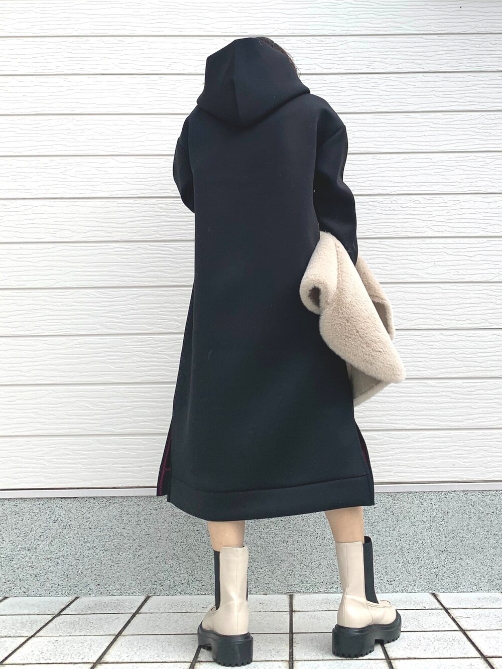 ベージュ系のベスト、ホワイト系のブーツ、ブラック系のワンピースを着用したレディースの秋コーディネートの3枚目の写真