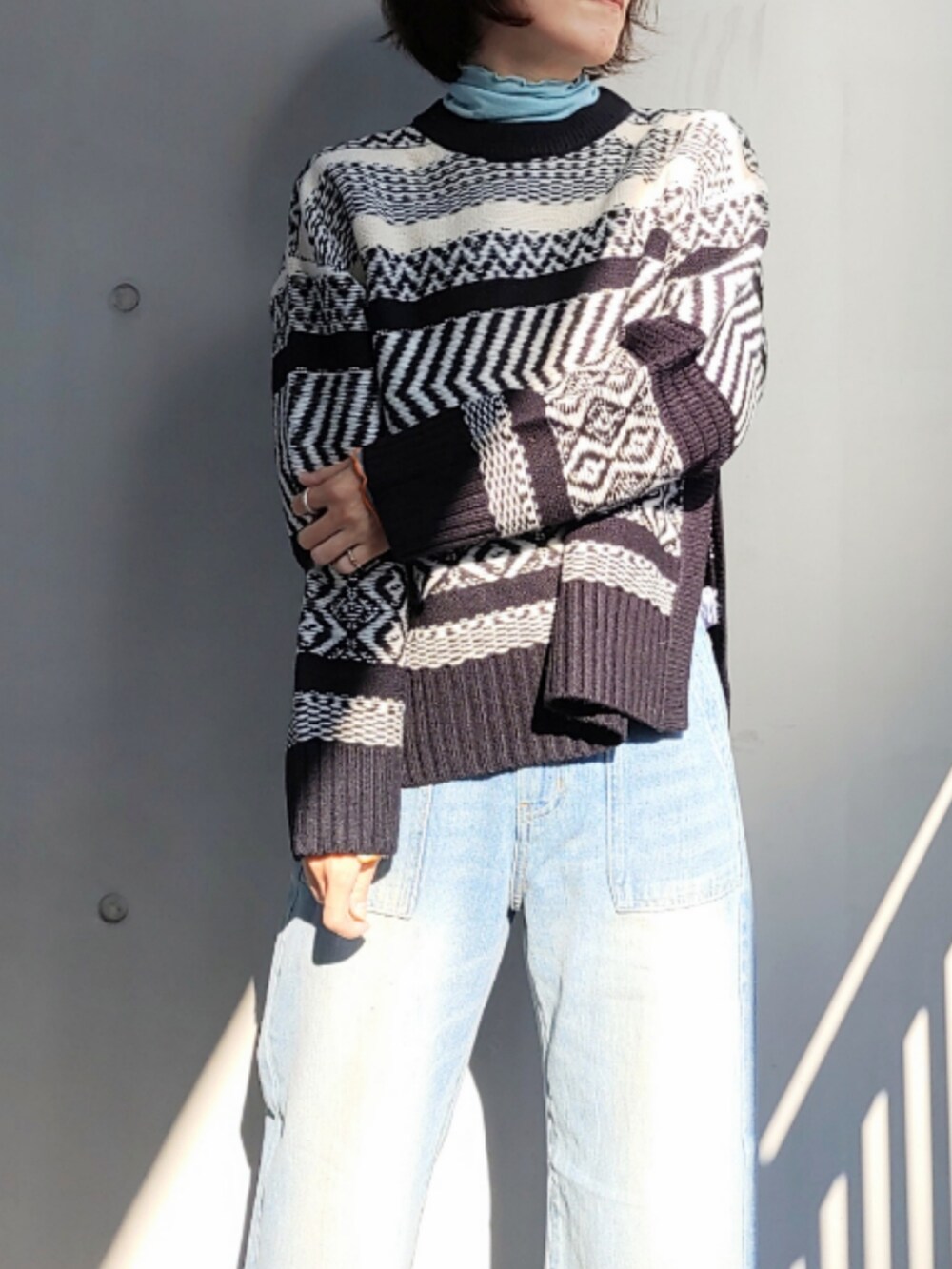 ブルー系のデニムパンツ、ブラック系のニット/セーター、ブルー系のTシャツ/カットソーを着用したレディースの秋コーディネートの4枚目の写真