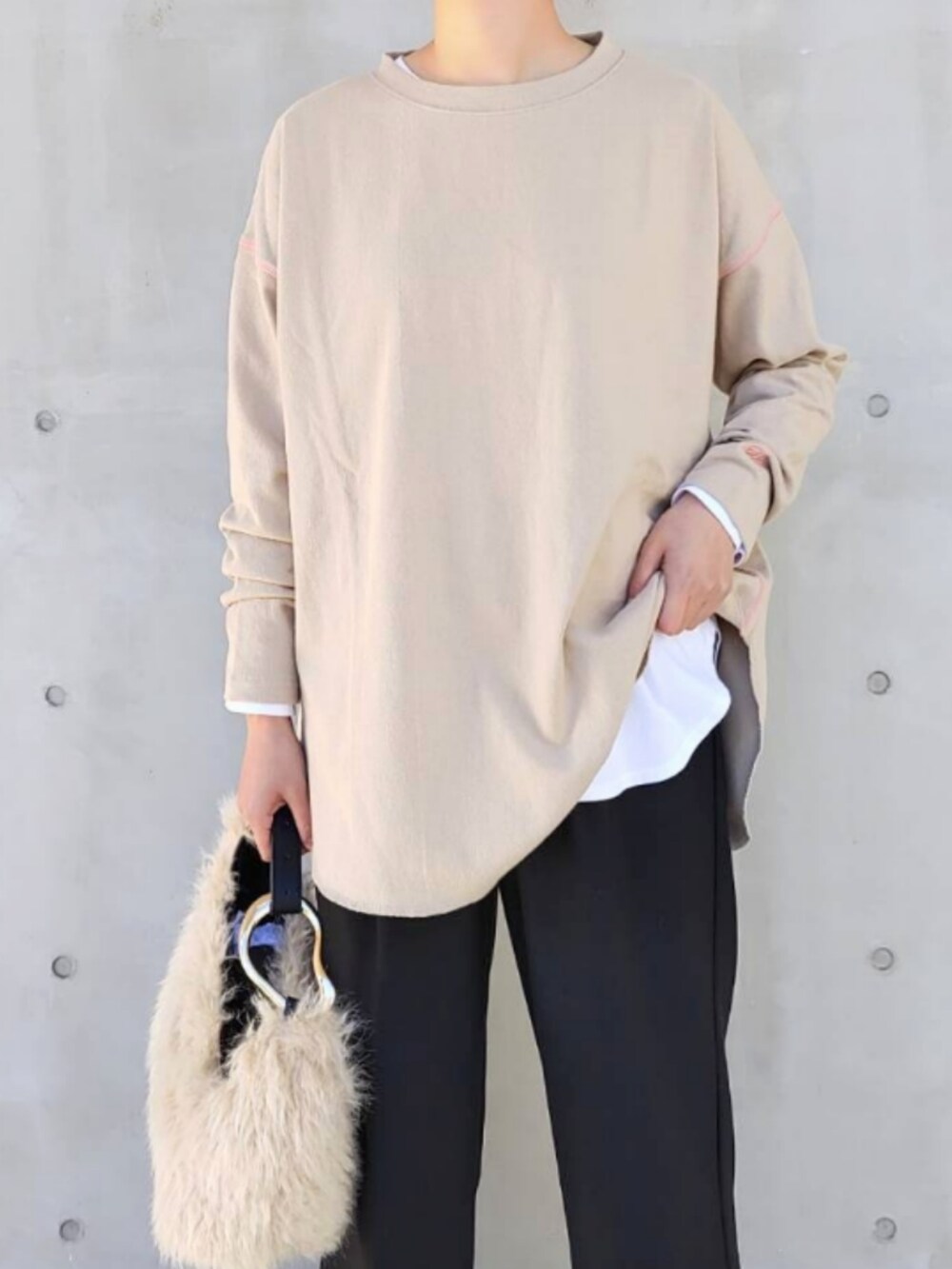 ベージュ系のTシャツ/カットソー、ベージュ系のハンドバッグ、ブラック系のスラックスを着用したレディースの秋コーディネートの3枚目の写真