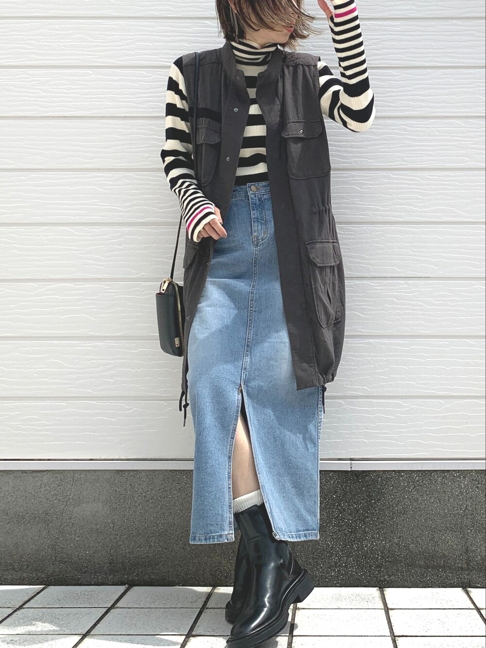 ブラック系のベスト、ホワイト系のニット/セーター、ブルー系のデニムスカートを着用したレディースの夏コーディネートの2枚目の写真