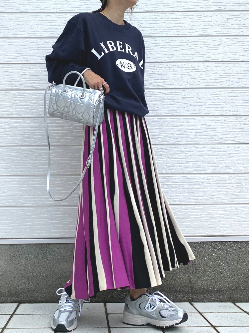 ブルー系のスウェット、ピンク系のスカート、シルバー系のスニーカーを着用したレディースの秋コーディネートの2枚目の写真