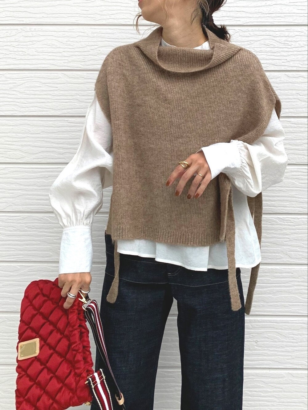 イエロー系のベスト、レッド系のショルダーバッグ、ブルー系のデニムパンツを着用したレディースの秋コーディネートの3枚目の写真