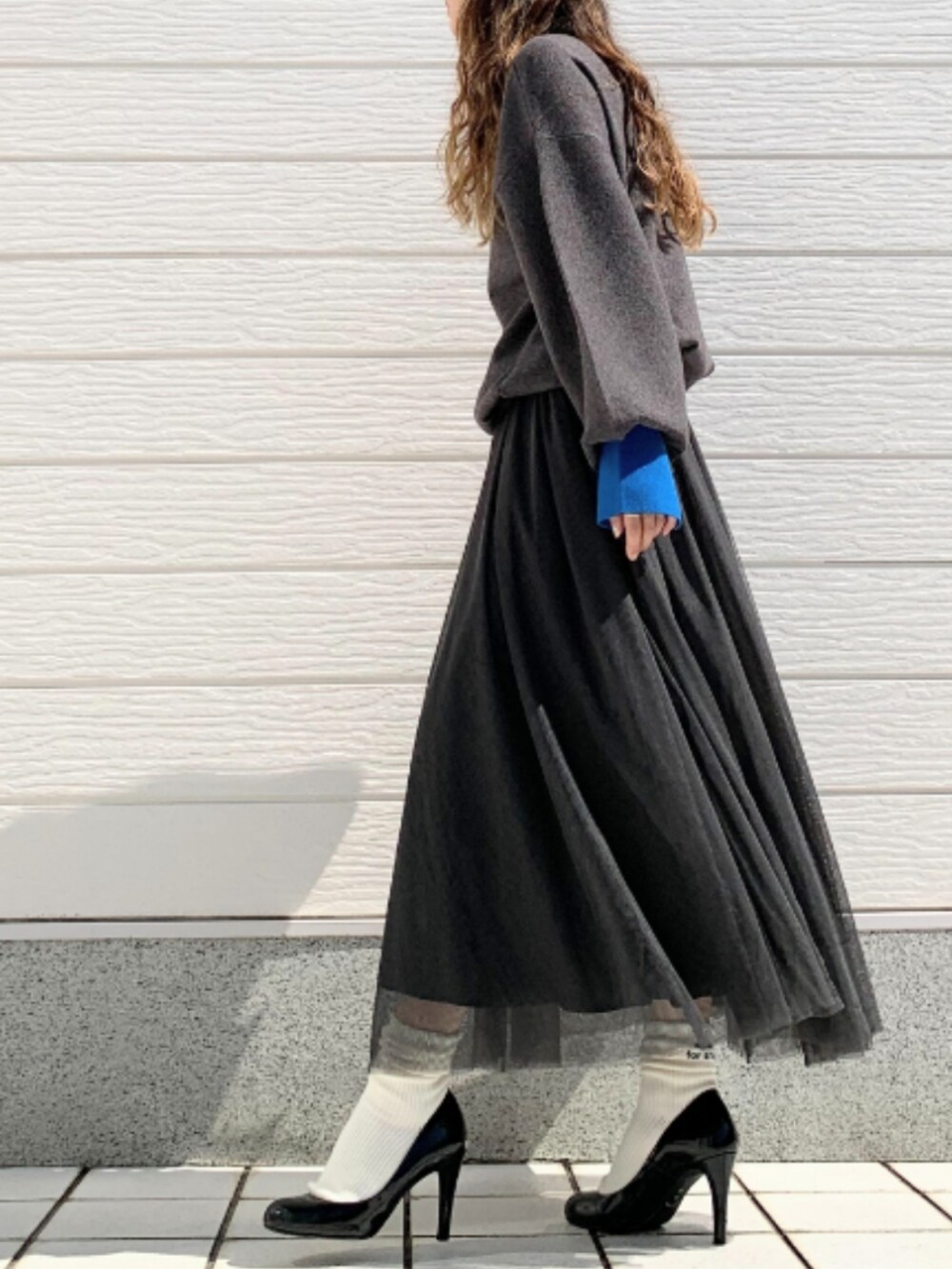 ブラック系のスカート、グレー系のニット/セーターを着用したレディースの秋コーディネートの2枚目の写真