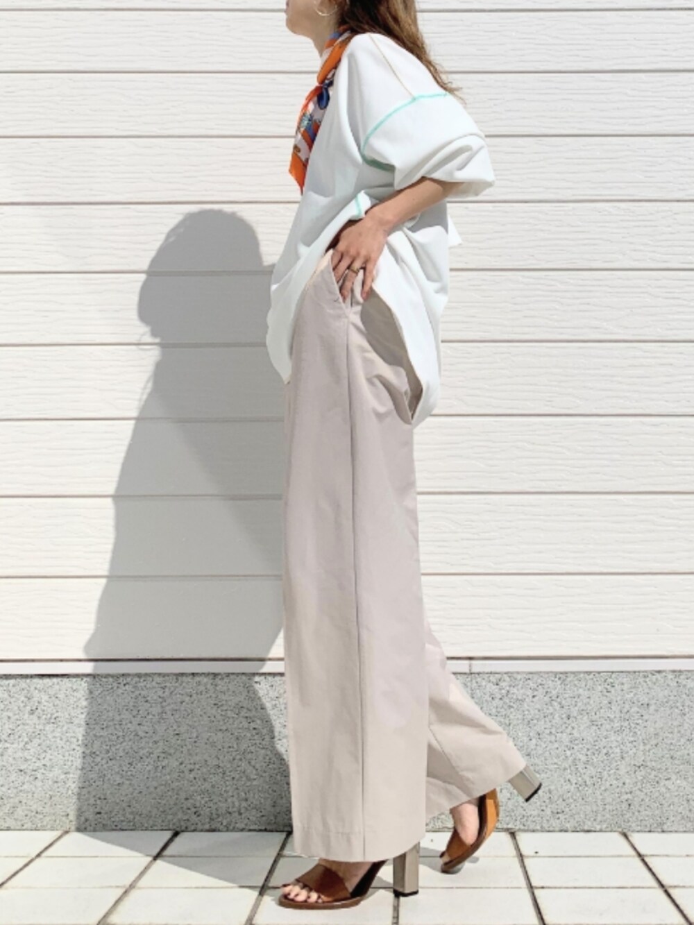 ホワイト系のTシャツ/カットソー、ブラック系のトートバッグ、ブラウン系のサンダルを着用したレディースの春コーディネートの3枚目の写真