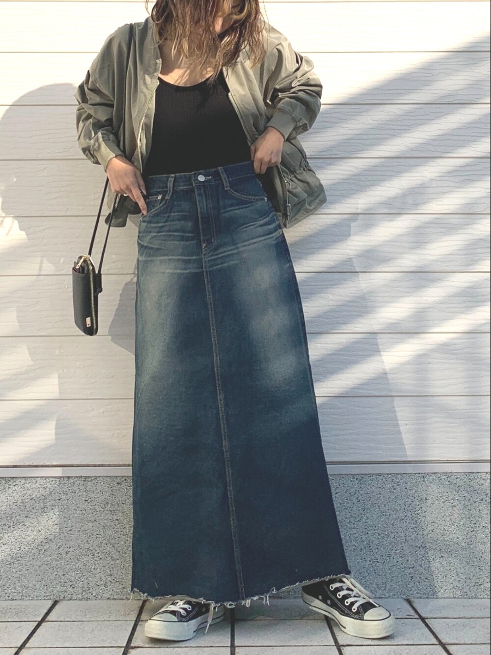 ブラック系のキャミソール、ブルー系のデニムスカート、ブラック系のスニーカーを着用したレディースの冬コーディネートの5枚目の写真