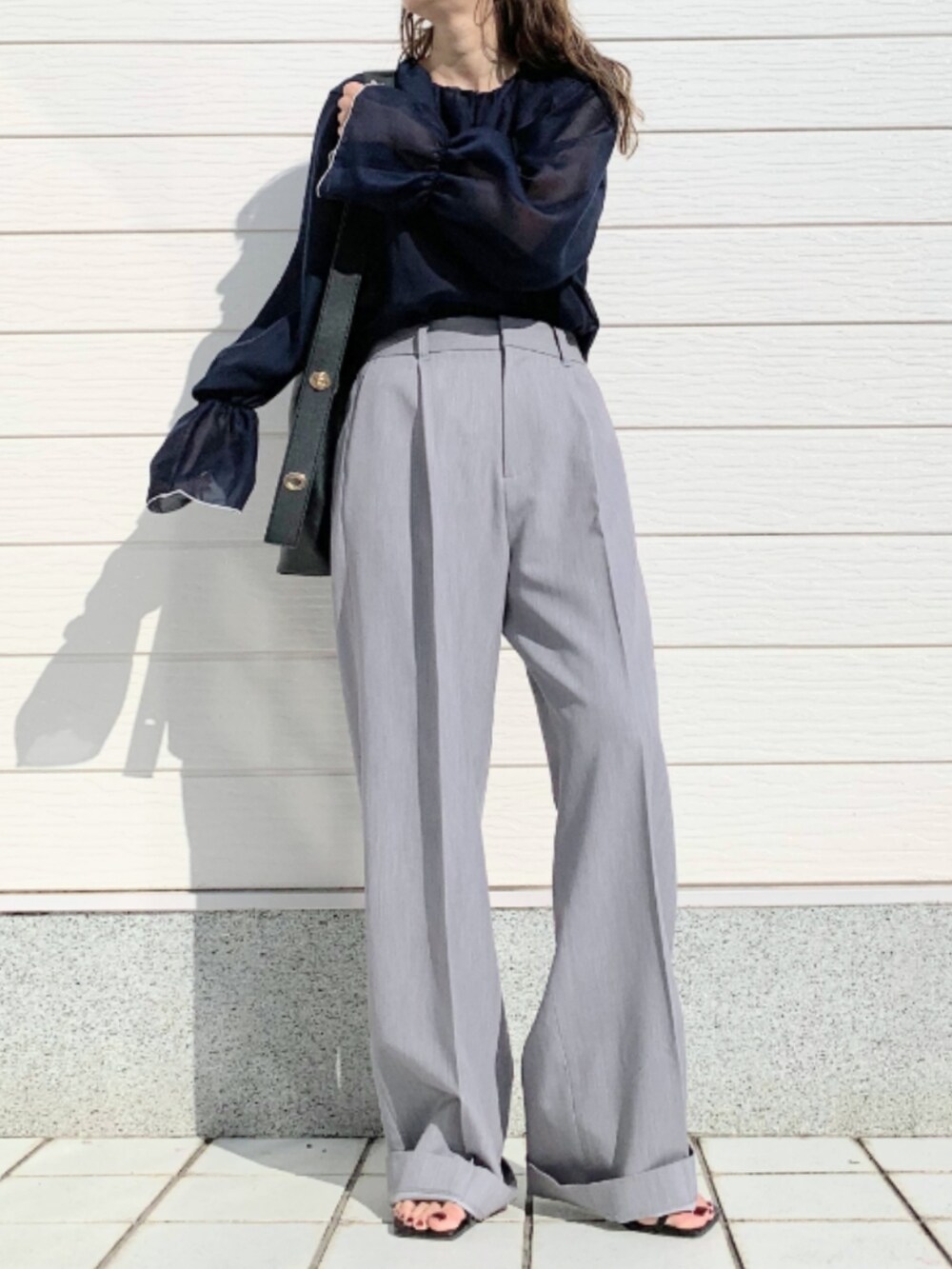 グレー系のスラックス、ブラック系のトートバッグ、ブルー系のシャツ/ブラウスを着用したレディースの春コーディネートの2枚目の写真