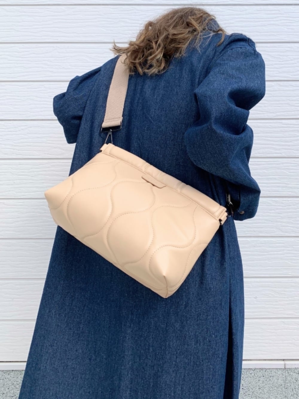 ブラック系のサンダル、ブルー系のシャツワンピース、ベージュ系のクラッチバッグを着用したレディースの春コーディネートの5枚目の写真