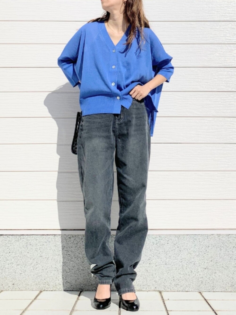 グレー系のデニムパンツ、ブラック系のショルダーバッグ、ブルー系のカーディガン/ボレロを着用したレディースの春コーディネートの2枚目の写真