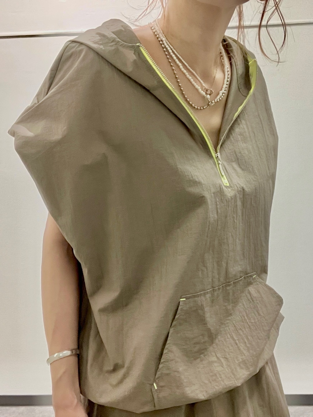 グリーン系のパーカー、グリーン系のスカート、ブラック系のトートバッグを着用したレディースの夏コーディネートの4枚目の写真