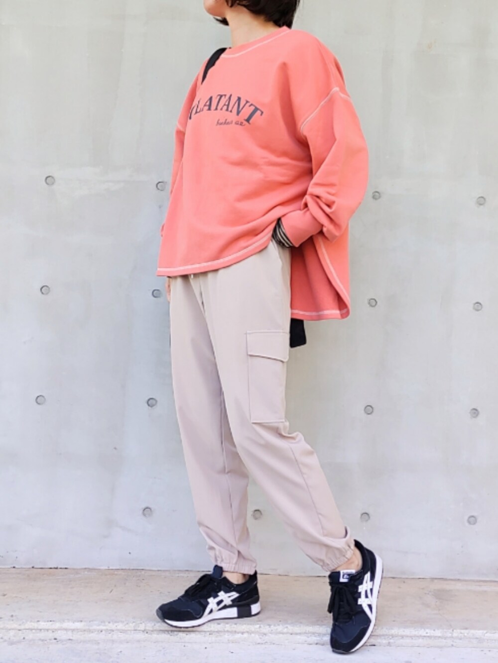 ベージュ系のカーゴパンツ、ブラック系のスニーカー、ブラック系のバックパック/リュックを着用したレディースの秋コーディネートの2枚目の写真