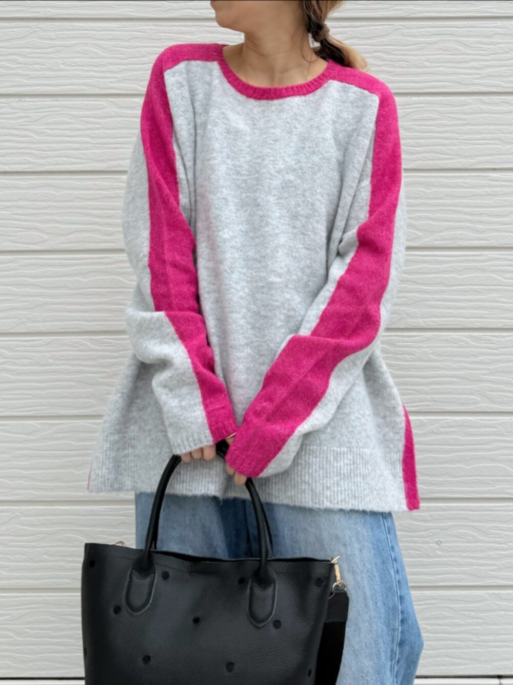 ブルー系のデニムパンツ、ブラック系のトートバッグ、グレー系のニット/セーターを着用したレディースの冬コーディネートの3枚目の写真