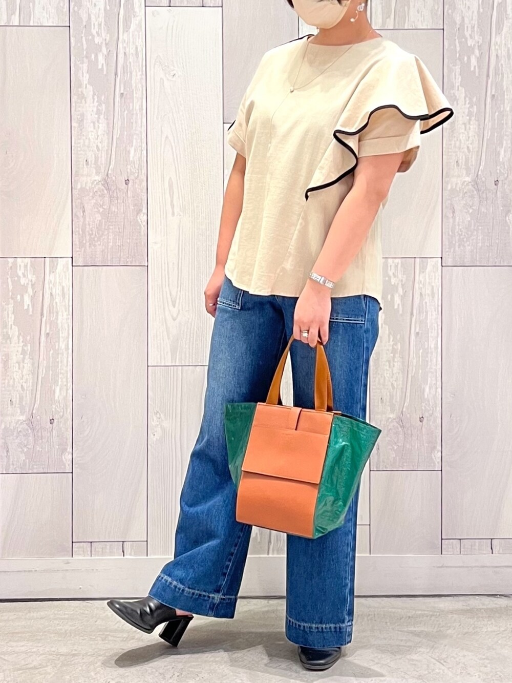 グリーン系のトートバッグ、ブルー系のデニムパンツ、ベージュ系のシャツ/ブラウスを着用したレディースの夏コーディネートの2枚目の写真