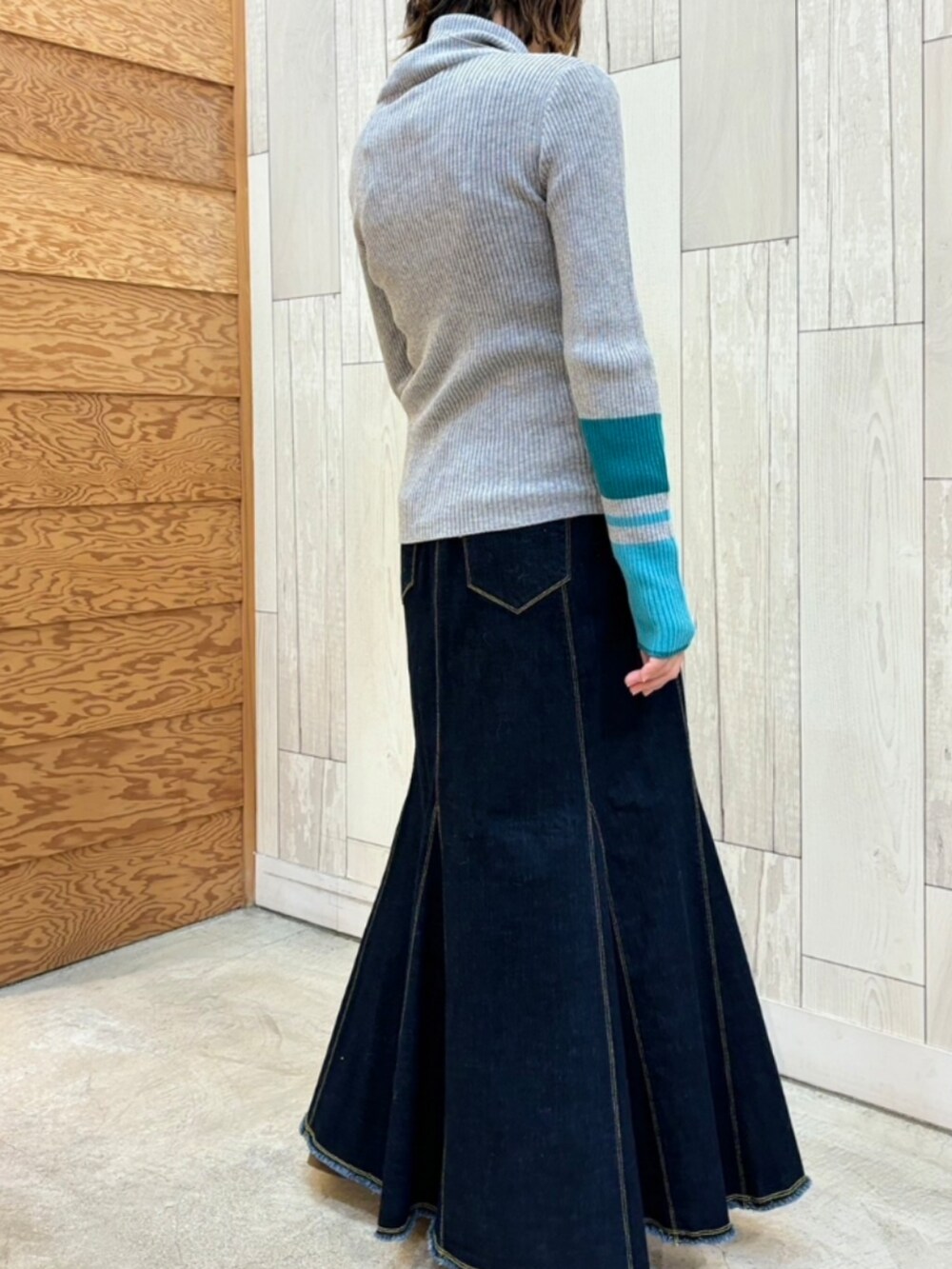 ブラック系のデニムスカート、グレー系のニット/セーター、ベージュ系のベストを着用したレディースの冬コーディネートの2枚目の写真