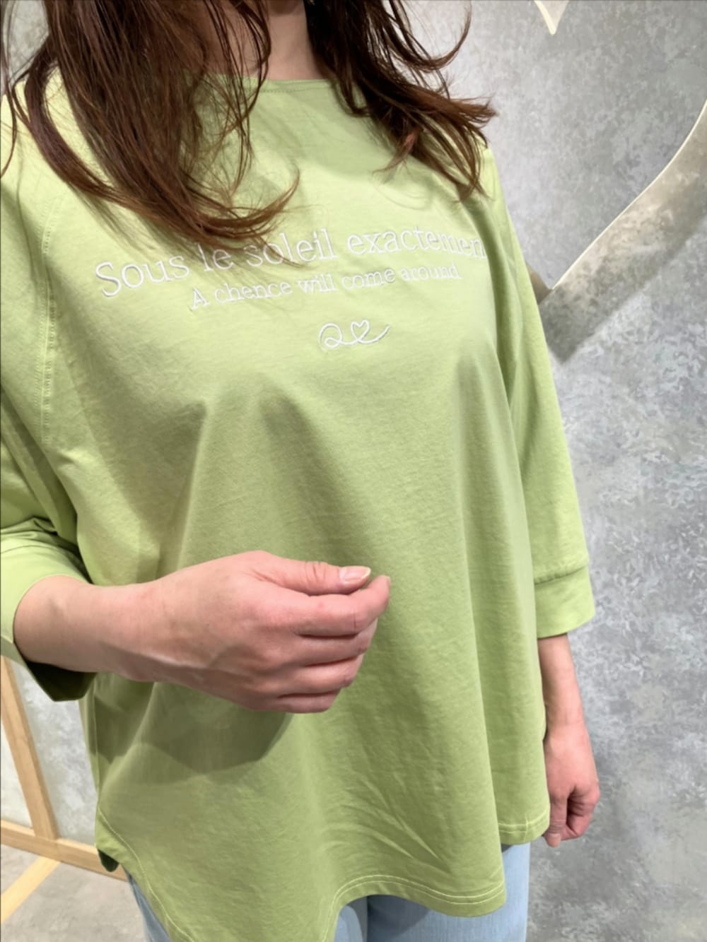 ブルー系のデニムパンツ、グリーン系のTシャツ/カットソー、ベージュ系のノーカラーコートを着用したレディースの冬コーディネートの3枚目の写真