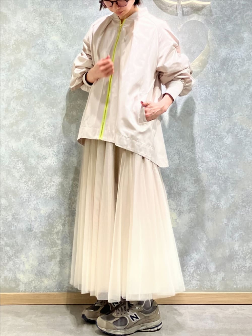 ゴールド系のスカート、ベージュ系のブルゾン、ホワイト系のTシャツ/カットソーを着用したレディースの冬コーディネートの2枚目の写真