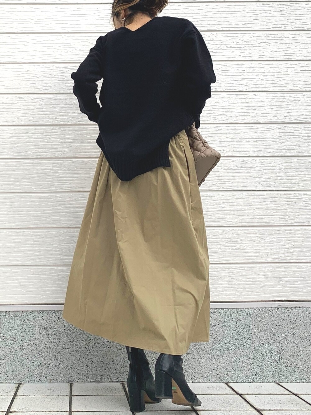 ベージュ系のスカート、ベージュ系のショルダーバッグ、ブラック系のニット/セーターを着用したレディースの冬コーディネートの3枚目の写真