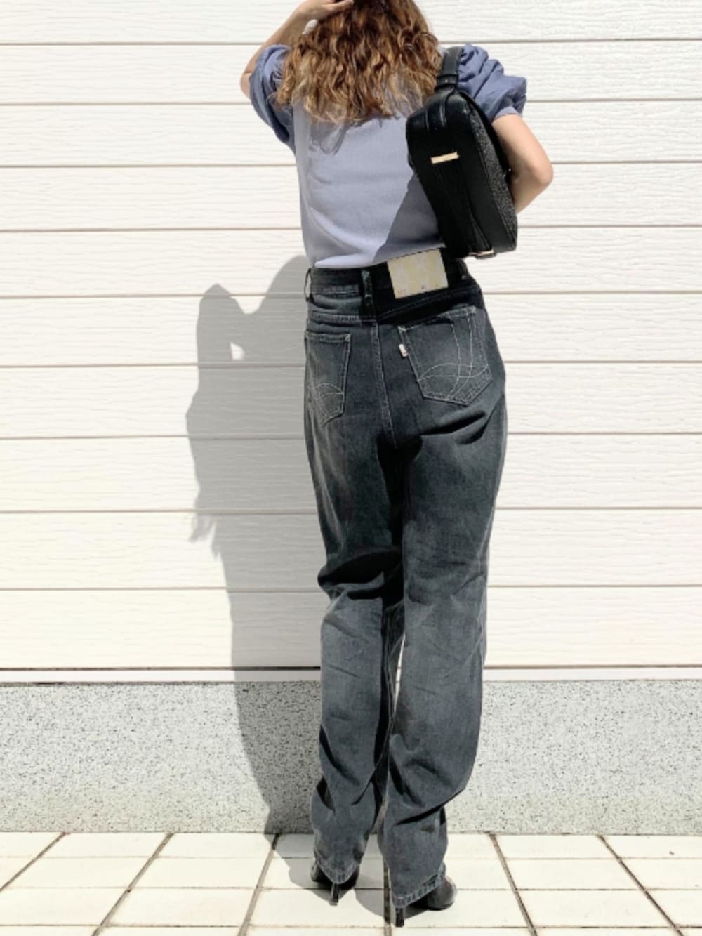 グレー系のデニムパンツ、ブラック系のショルダーバッグ、ブルー系のニット/セーターを着用したレディースの春コーディネートの2枚目の写真