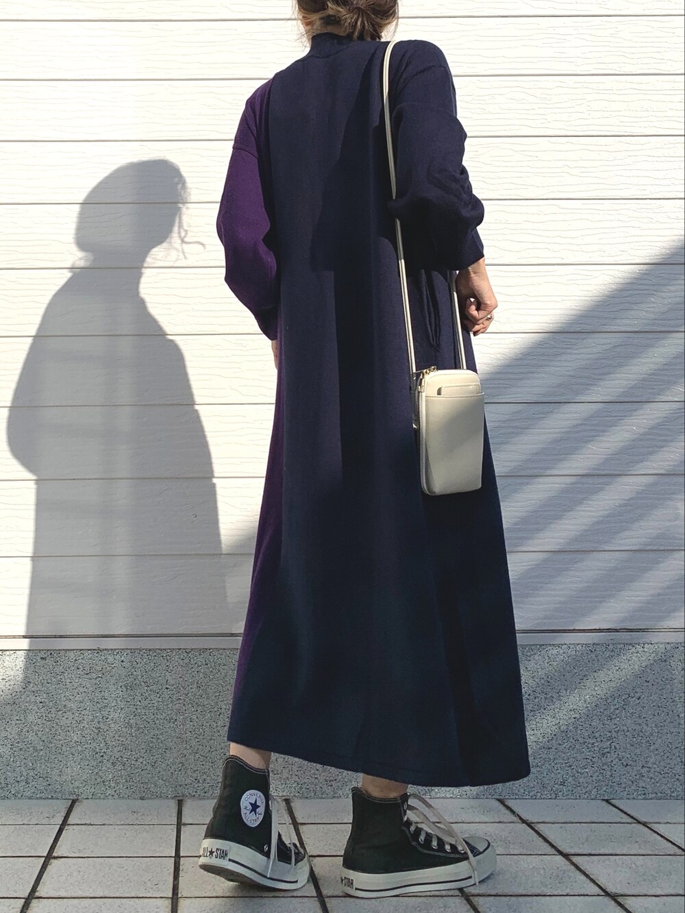 ブルー系のワンピース、ブラック系のスニーカー、ホワイト系のショルダーバッグを着用したレディースの秋コーディネートの3枚目の写真
