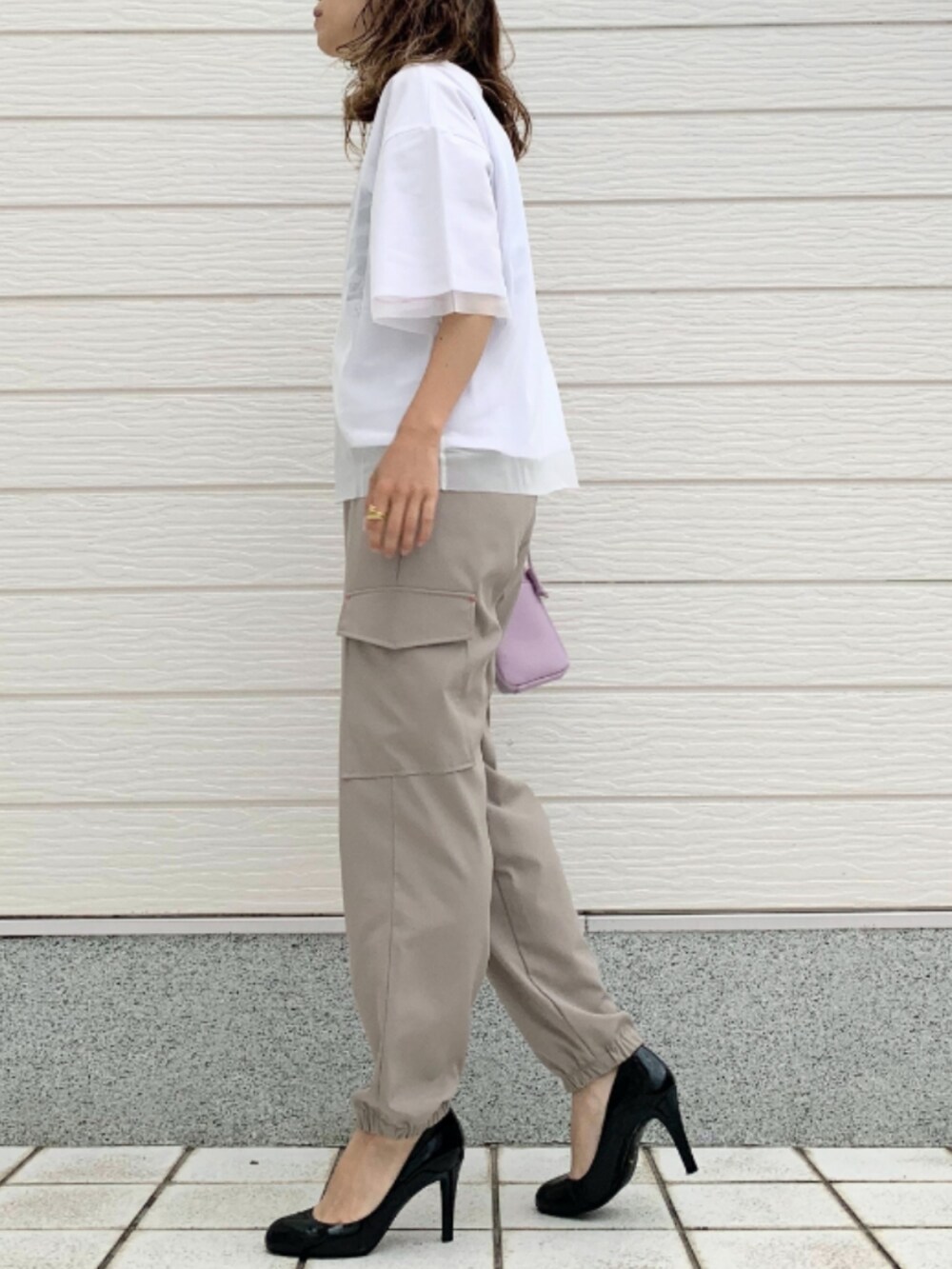 ベージュ系のカーゴパンツ、ホワイト系のTシャツ/カットソー、パープル系のショルダーバッグを着用したレディースの春コーディネートの2枚目の写真
