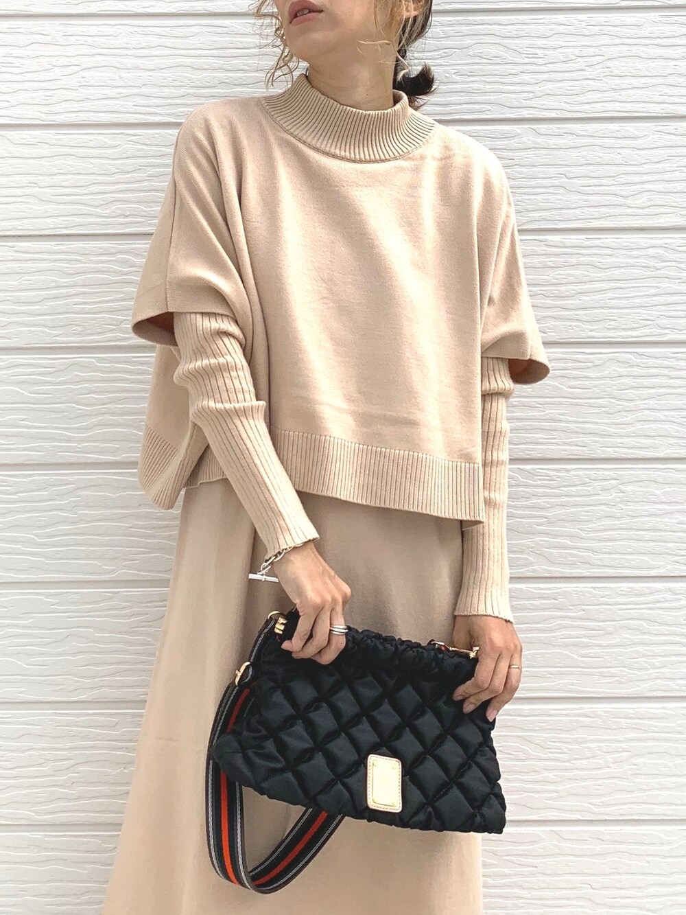 ブラック系のショルダーバッグ、ベージュ系のワンピース、シルバー系のブレスレットを着用したレディースの秋コーディネートの3枚目の写真