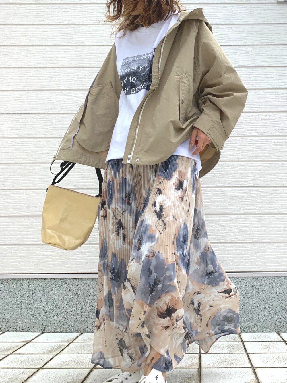 イエロー系のスカート、ホワイト系のスニーカー、ベージュ系のショルダーバッグを着用したレディースの春コーディネートの2枚目の写真