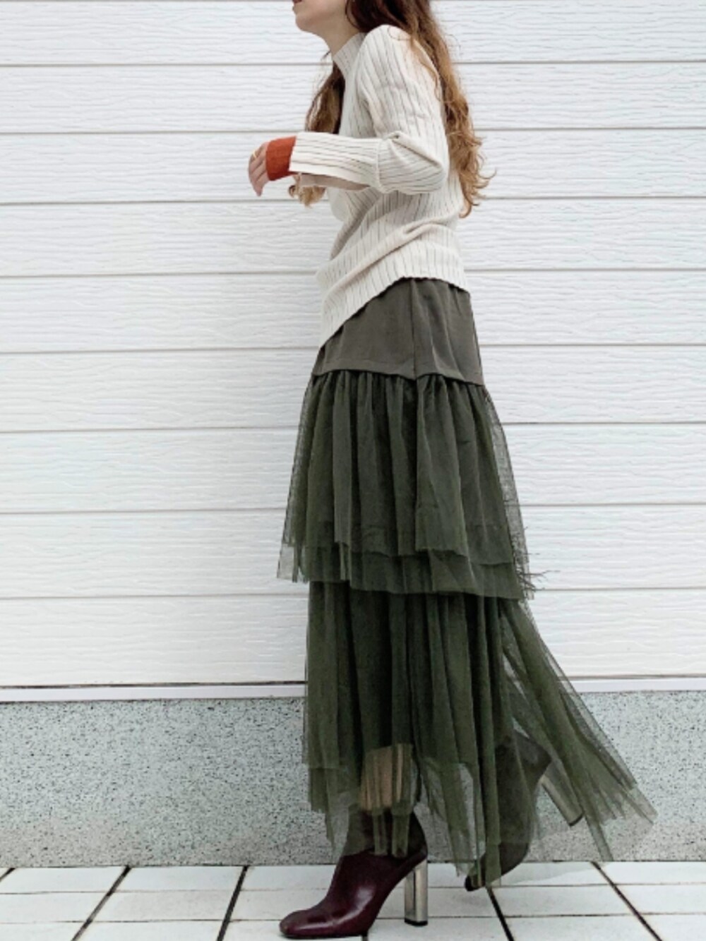 ブラウン系のブーツ、ホワイト系のニット/セーター、ブラック系のクラッチバッグを着用したレディースの秋コーディネートの2枚目の写真