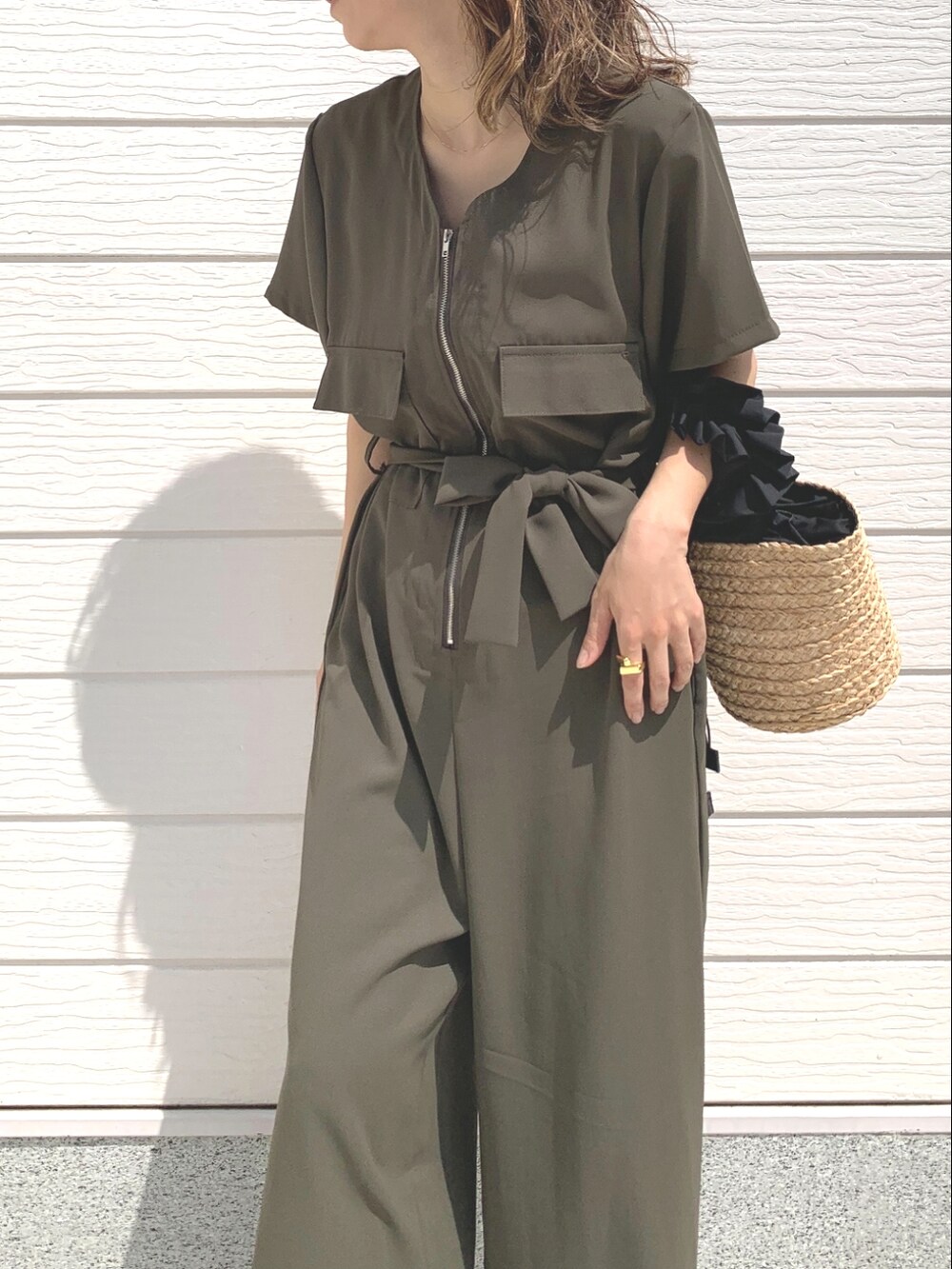 ブラック系のかごバッグ、グリーン系のつなぎ/オールインワン、ブラック系のサンダルを着用したレディースの春コーディネートの4枚目の写真