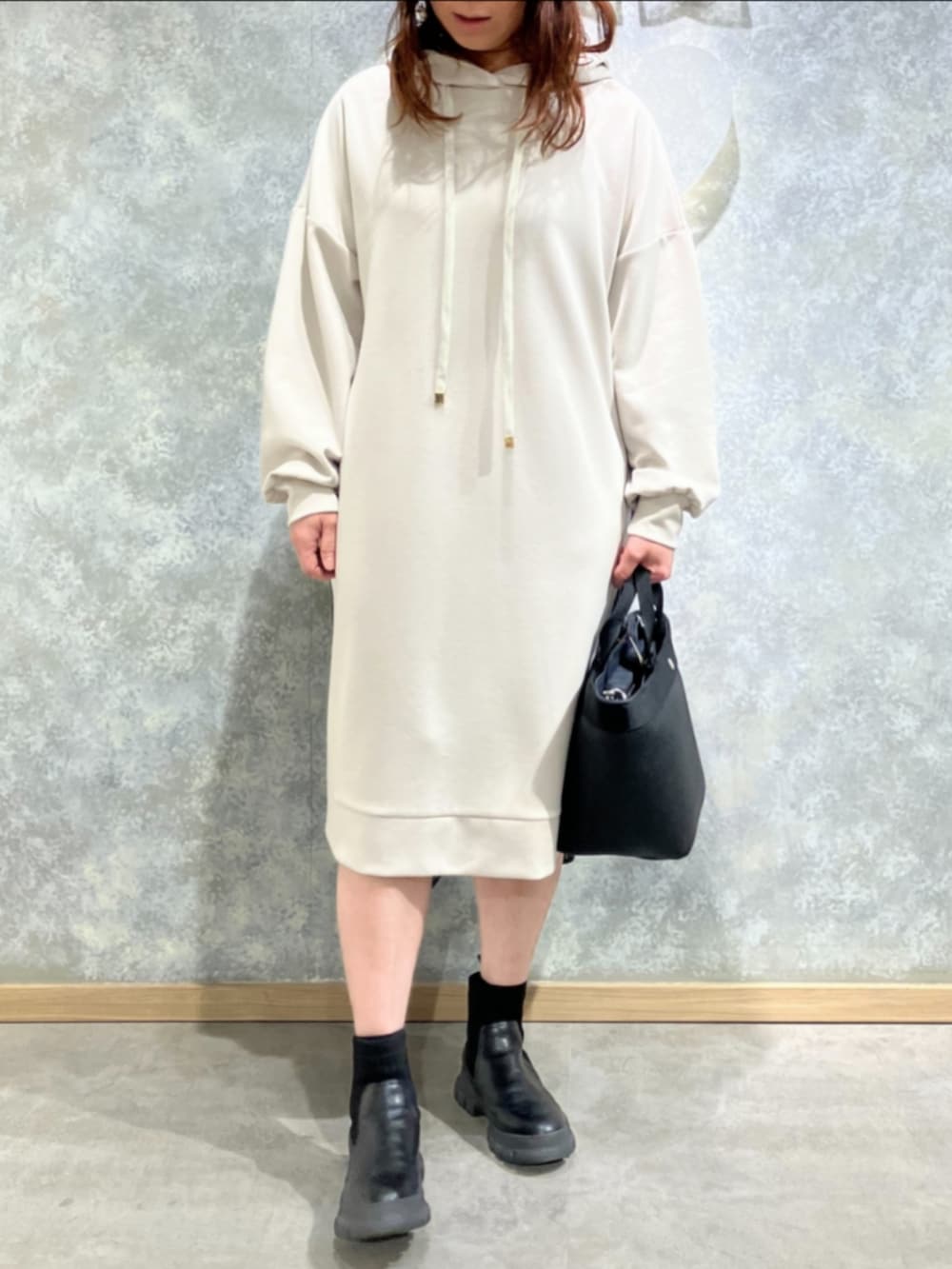 ブラック系のトートバッグ、ホワイト系のワンピースを着用したレディースの冬コーディネートの2枚目の写真