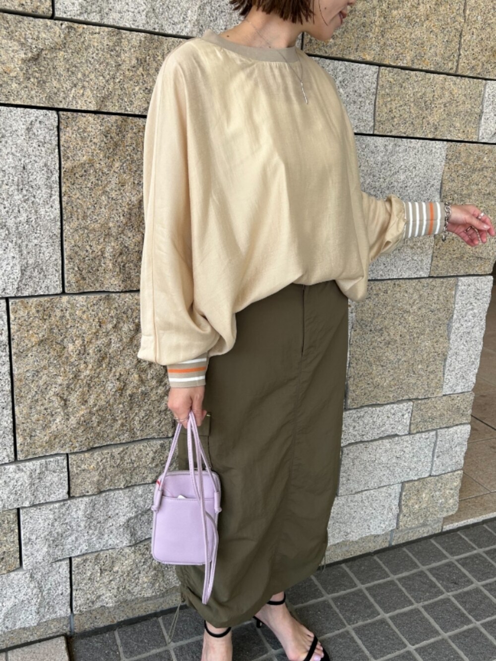 グリーン系のスカート、パープル系のショルダーバッグ、ベージュ系のシャツ/ブラウスを着用したレディースの春コーディネートの2枚目の写真