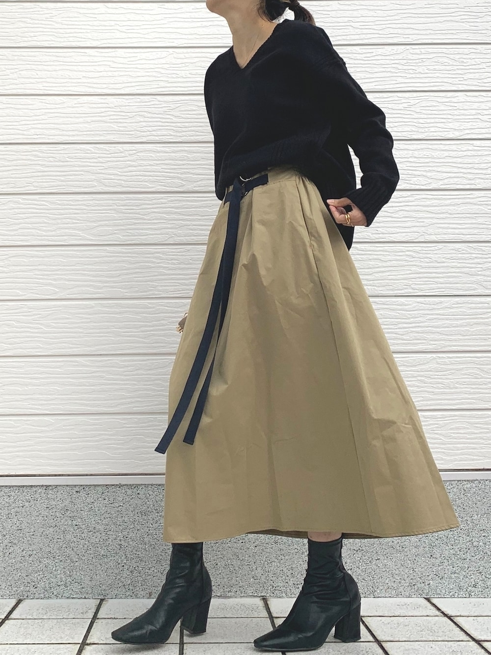 ベージュ系のスカート、ベージュ系のショルダーバッグ、ブラック系のニット/セーターを着用したレディースの冬コーディネートの2枚目の写真